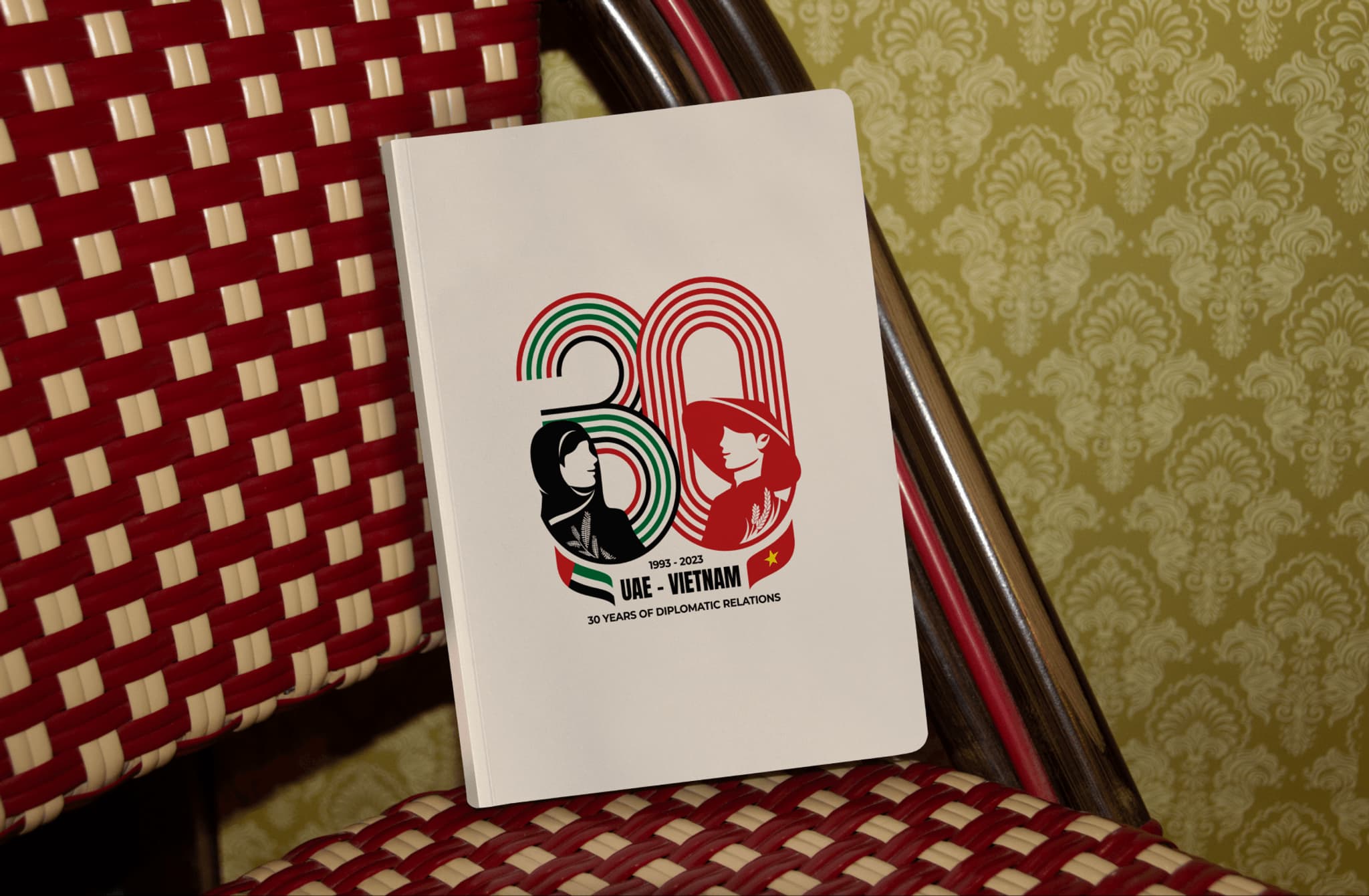 White notebook featuring a design celebrating 30 years of UAE-Vietnam diplomatic relations, placed on a patterned chair.