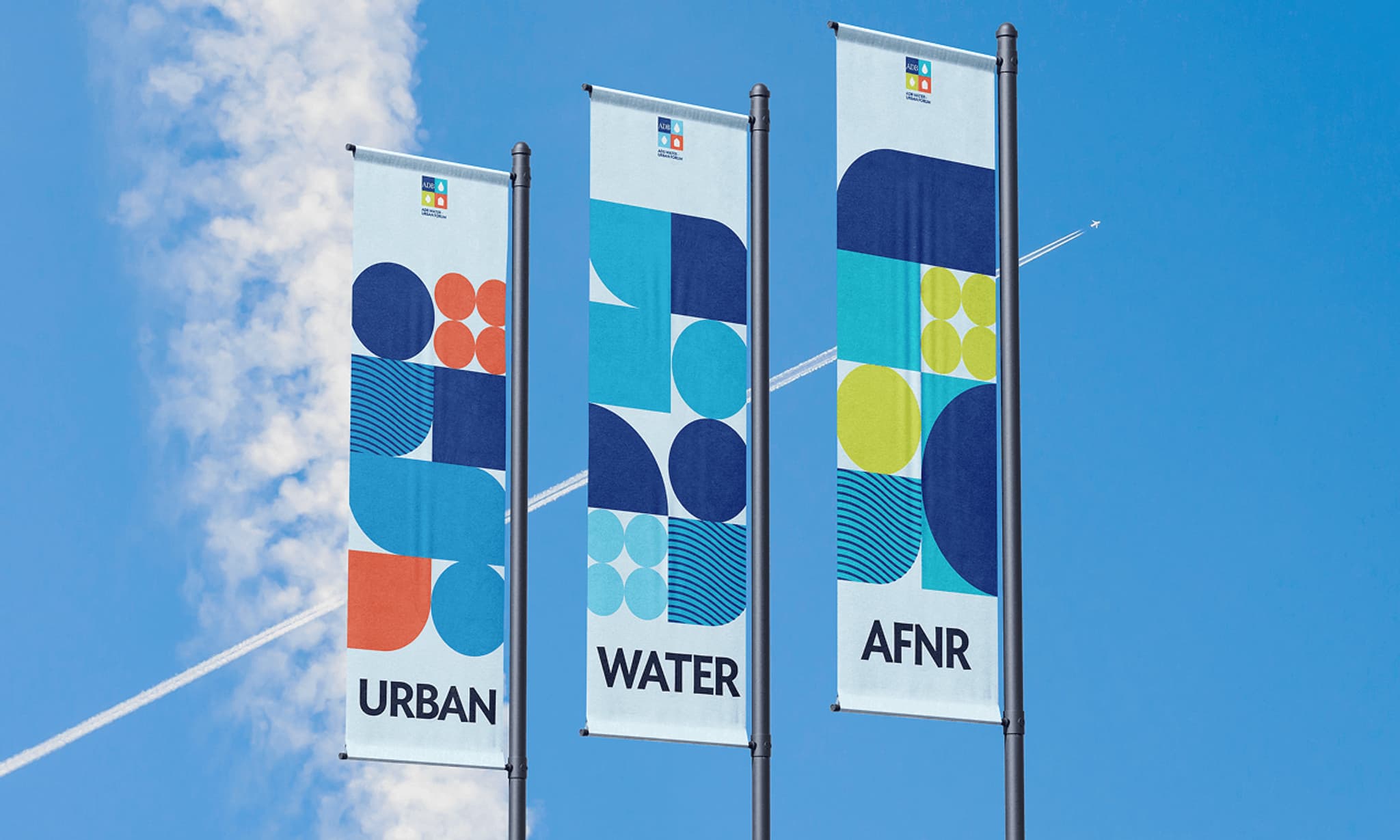 Banners displaying the words "Urban," "Water," and "AFNR" against a clear blue sky, featuring geometric designs in vibrant colors.