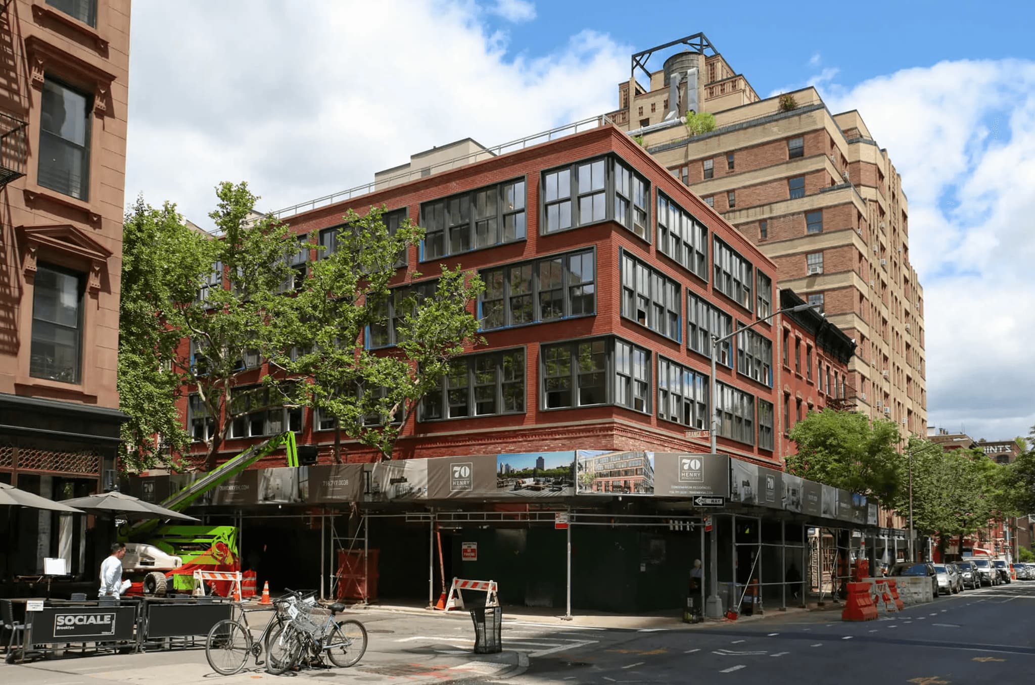 Renovated brick building in Brooklyn featuring large windows, outdoor seating, and construction scaffolding.