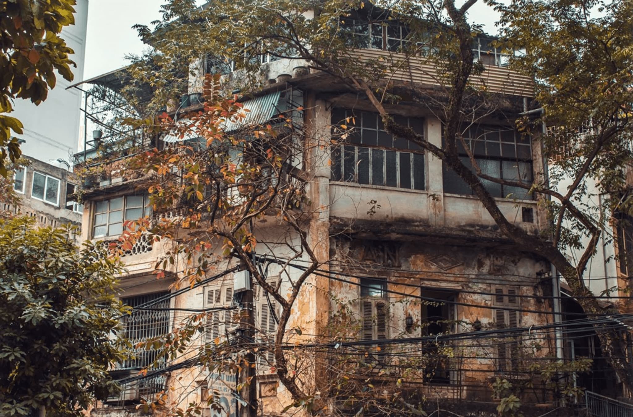 Historic Hanoi building surrounded by lush greenery, showcasing unique architecture and urban charm.