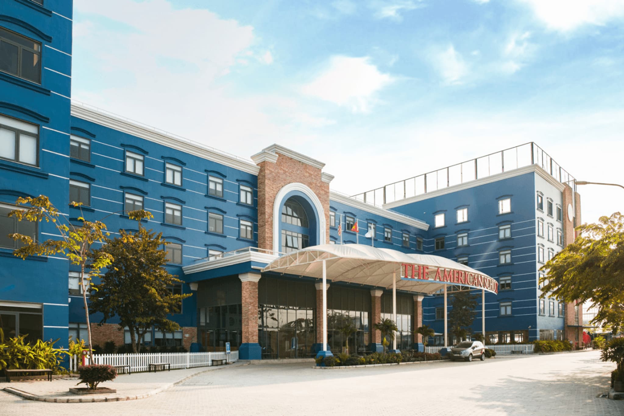 Modern hotel exterior with blue facade and welcoming entrance, set against a bright sky. Ideal for travel and accommodation searches.