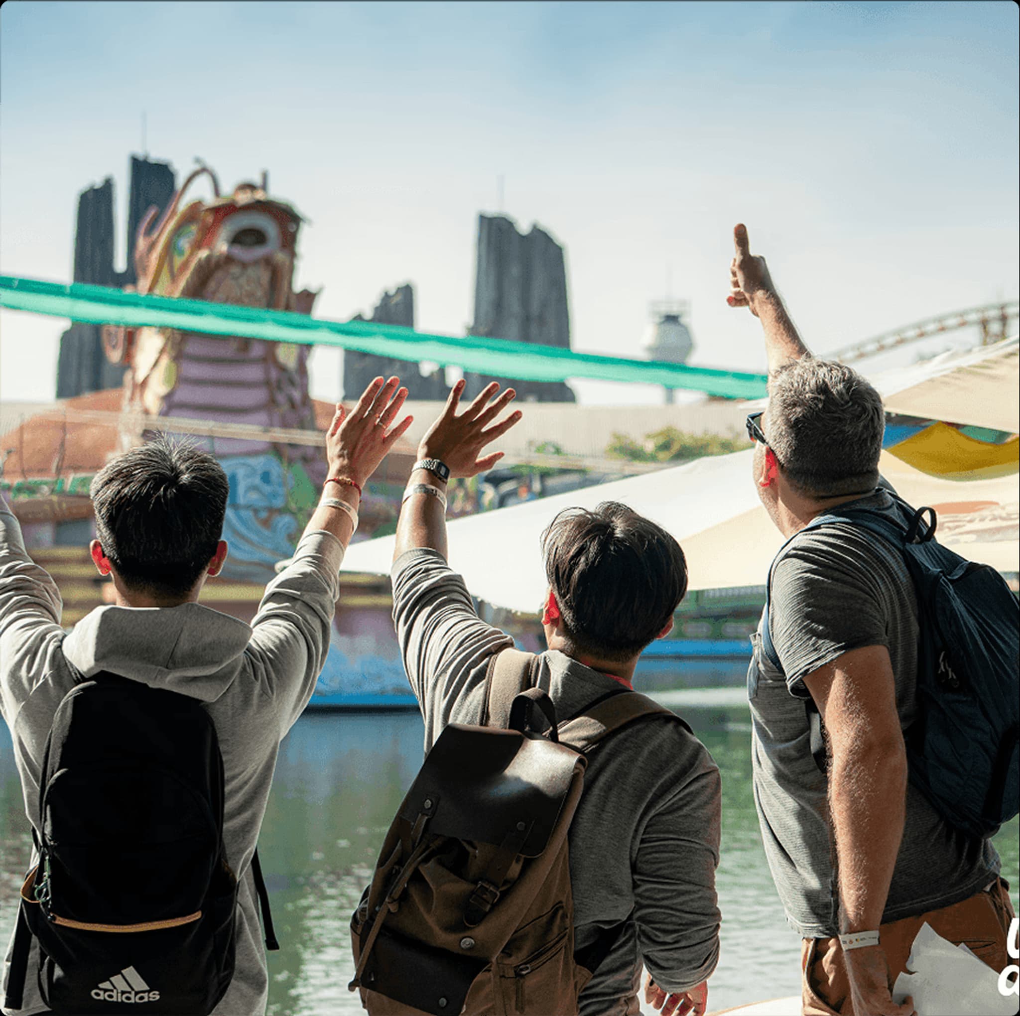 Crowd enjoying a vibrant theme park, featuring colorful attractions and scenic views in the background.