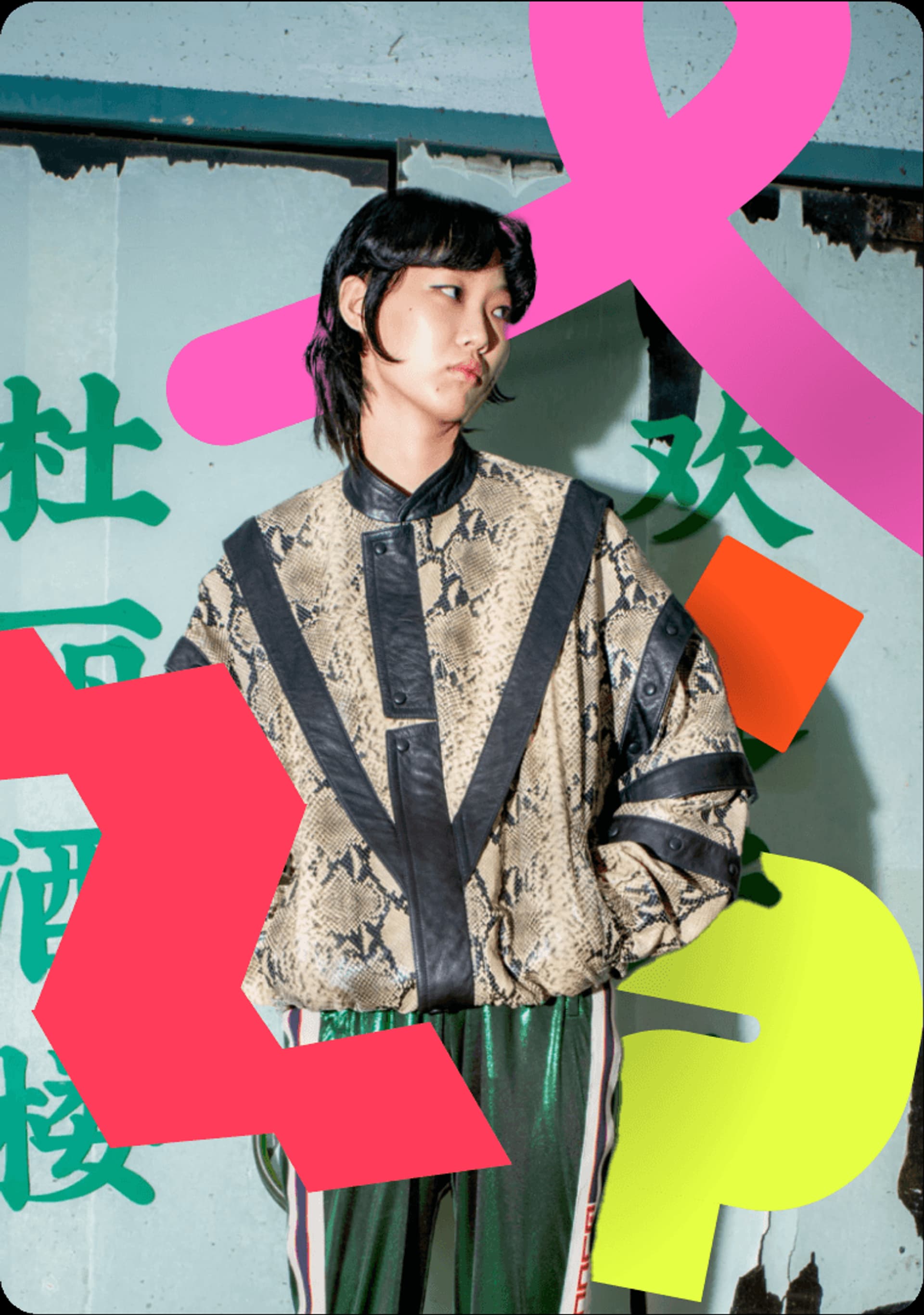 Fashion-forward model wearing a snake-print bomber jacket and vibrant green pants against a colorful graffiti background.